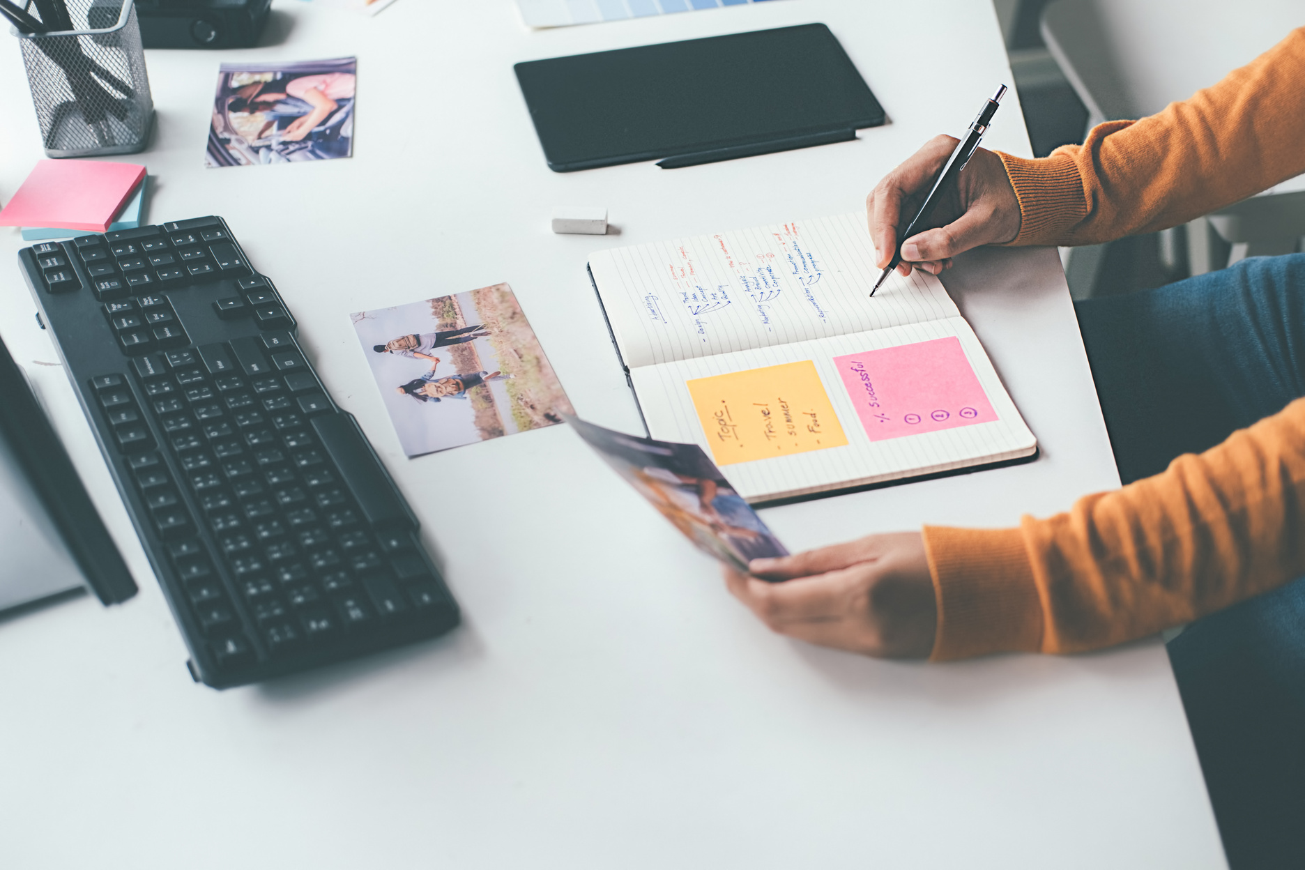 Advertising Agency Designer Writing Plans on Notebook